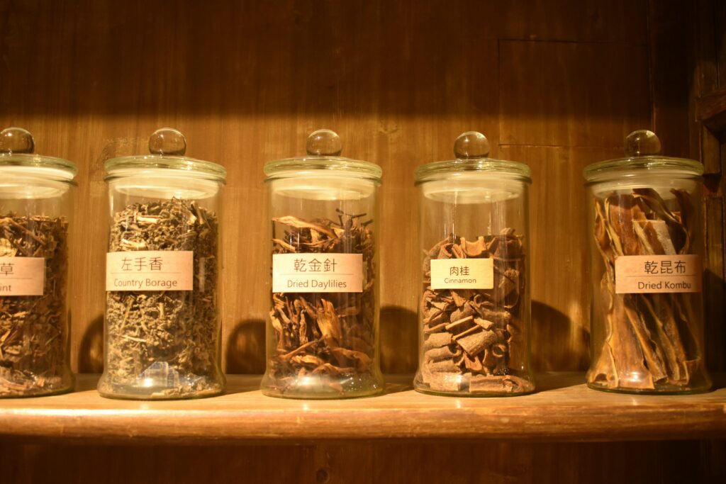 Glass jars filled with dried herbs on a wooden kitchen shelf