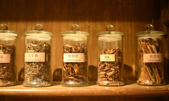 Glass jars filled with dried herbs on a wooden kitchen shelf